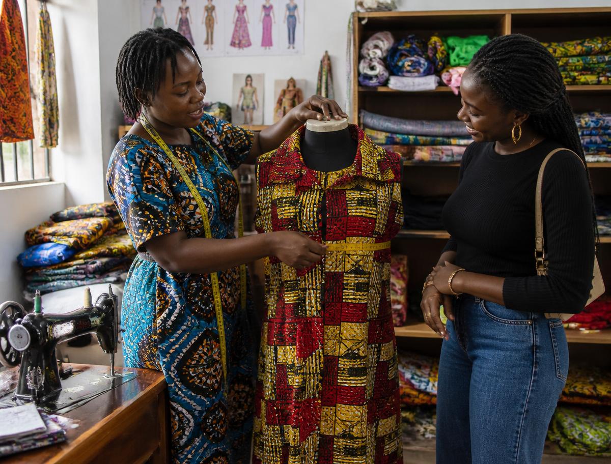 Tailor measuring an ankara outfit in her studio with a customer